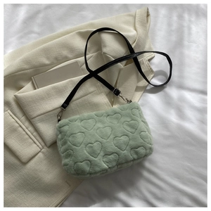 Détail du sac en peluche vert clair avec motifs de cœurs 3D et bandoulière réglable