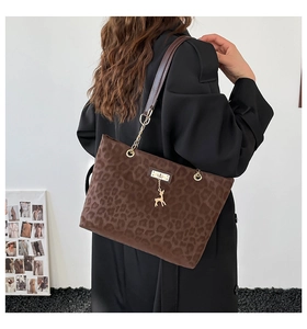 Detail of leopard print tote bag with gold deer charm and chain shoulder strap
