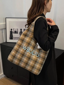 Detail of vintage plaid tote bag with blue WBDLID embroidery and white plush charm