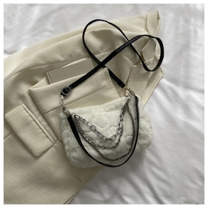 Détail d'un sac en fausse fourrure blanche avec gaufrage cœur et chaînes argentées