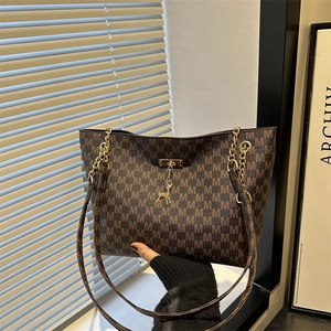 Große braune Tote Bag mit M-Muster, goldener Kette und einem Hirsch-Anhänger Detail