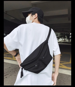 Rear view of a spacious black waterproof crossbody bag worn by a person in white T-shirt