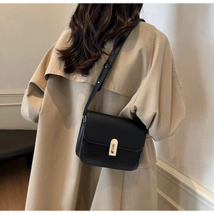 Detail of a black matte leather square crossbody bag with a gold rectangular twist lock