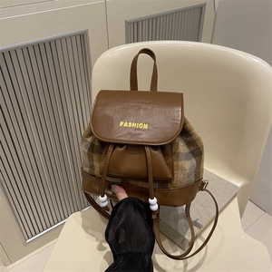 Vintage college style backpack with brown leather patchwork and plaid fabric on a chair