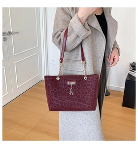Detail of burgundy leopard print tote bag with gold chain strap and deer charm accessory
