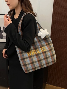 Detail of vintage plaid tote bag with yellow embroidery and cute plush puppy charm