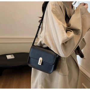 Detail of minimalist black leather crossbody bag with elegant gold metal twist lock
