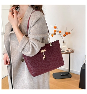 Detail of burgundy leopard print tote bag with gold deer charm and sleek shoulder straps