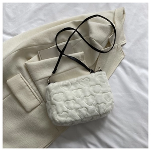 Détail du sac en fourrure blanche avec motifs cœurs gaufrés et bandoulière en cuir