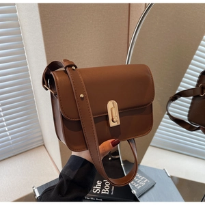 Detail view of caramel brown leather square bag with a golden metal buckle on mirror
