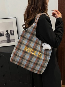 Macro shot of embroidered letters and star charm on the plaid canvas shoulder tote bag