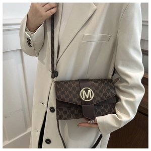 Primer plano del bolso bandolera marrón con estampado de letras y logo dorado metálico M