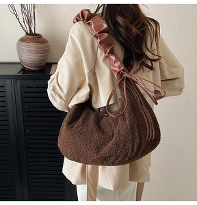 Brown fluffy faux fur hobo bag with stylish pleated leather strap on a model