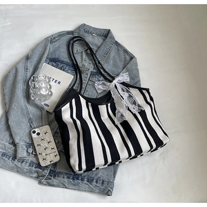 Detail of canvas tote bag with black and white stripes and white lace bow decoration
