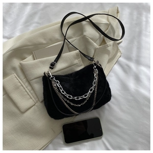 Détail d'un sac bandoulière en peluche noire avec chaînes argentées et lanière en cuir