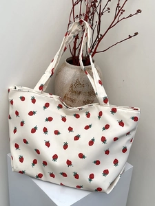 Detail of strawberry print on large capacity nylon tote bag against minimalist background