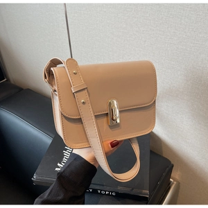 Detailed view of the sleek golden oval twist lock on a beige leather crossbody bag