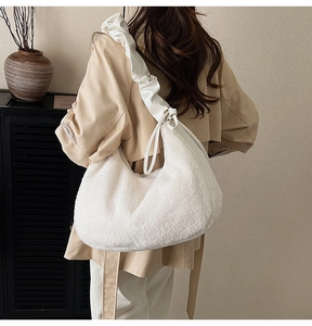 Detail of white faux fur hobo bag with elegant ruffled satin strap on a model