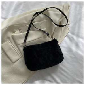 Détail d'un sac en peluche noir à motifs de cœurs et boucle argentée ajustable