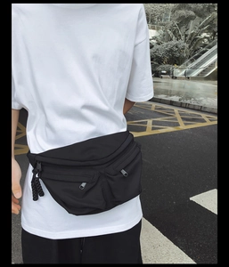Detail of multi-pocket black nylon chest bag showing crossbody fit and zipper storage