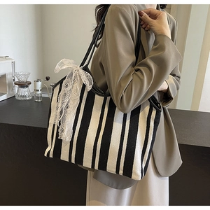 Detailed view of striped canvas tote with lace bow decoration in cafe setting