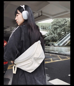 Detail of off-white multi-pocket crossbody bag with woven rope zipper pulls on model
