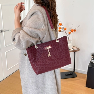 Burgundy leopard print shoulder bag with gold chain strap and deer charm on model
