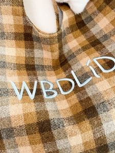 Detailed close-up of vintage plaid wool fabric and light blue WBDLID letter embroidery
