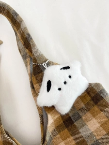 Close-up of white plush cartoon puppy charm on a vintage plaid wool shoulder bag