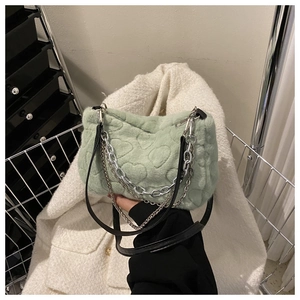 Détail d'un sac à main en peluche vert clair avec motifs de cœurs et chaîne en métal