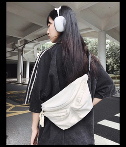Detail view of white utilitarian crossbody bag with decorative braided rope on street model