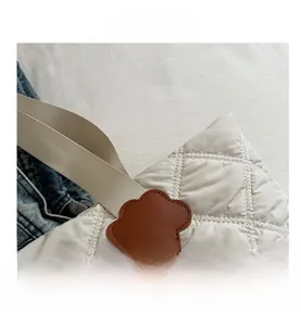 Detailed close-up of quilted tote bag featuring brown leather flower patch accent