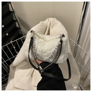 Détail d'un sac à main en peluche blanc avec texture gaufrée cœur et chaînes argentées