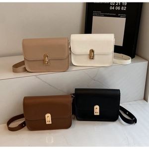 Minimalist square leather crossbody bags in four neutral colors on a marble stand