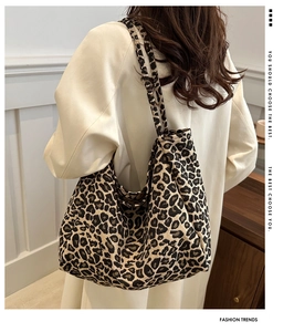 Detail view of large leopard print tote bag in textured fabric on female shoulder