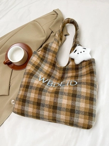 Detail of vintage plaid wool tote bag with blue embroidery and star plush pendant