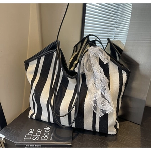 Close-up of black and white striped canvas tote bag with white lace bow on side