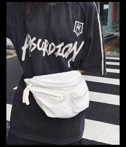 White crossbody chest bag with multiple zipper pockets and rope pulls on street background