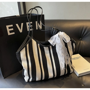 Detail of black and white striped tote bag with a large lace bow on a leather sofa
