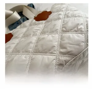Close-up of beige quilted tote bag showing soft diamond texture and cloud leather patch