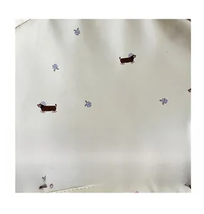 Vue détaillée du tissu crème avec de jolis motifs floraux et de chiots teckels