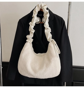 Close-up of white plush crescent shoulder bag with unique ruched leather strap details
