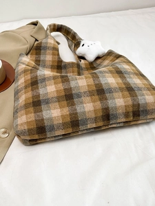 Detailed view of brown plaid wool tote bag with soft white star plush charm and autumn tones