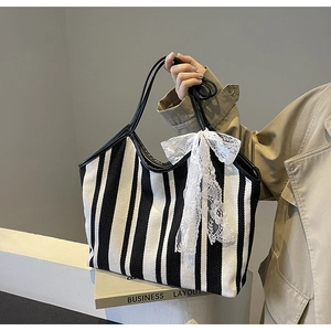 Detailed shot of striped canvas tote bag with white lace bow and black shoulder straps