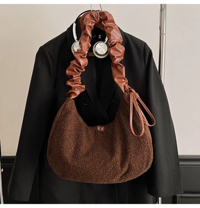 Detail of plush brown half-moon bag with scrunchie leather strap and dual metal zippers