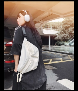 Detailed view of white crossbody bag with functional zip pockets and rope details