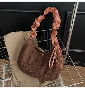 Detail of dark brown plush teddy fabric with glossy leather pleated handle on handbag