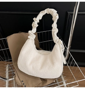 Detail of white plush shoulder bag with cream satin pleated handle in a shopping cart
