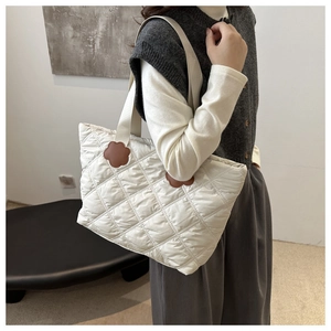 Close-up of white quilted tote bag featuring brown petal-shaped accents and woven straps