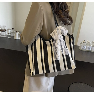 Detail of canvas tote bag featuring black and white stripes and a lace bow decoration